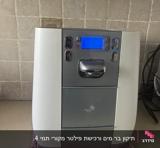 מכשיר מים על משטח מטבח עם מגבת אדומה